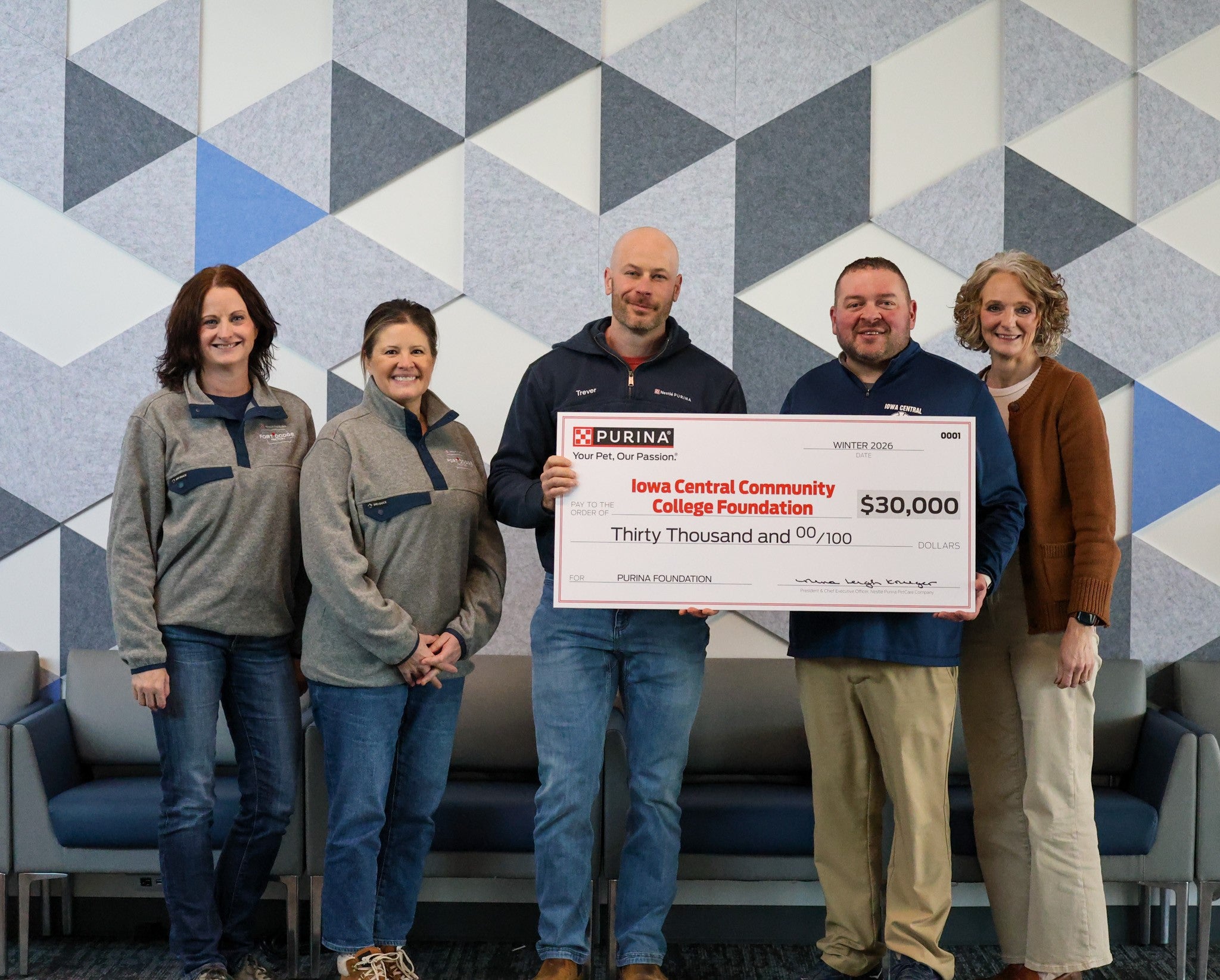 Five people stand in front of a geometric wall holding a $30,000 donation check for Iowa Central Community College Foundation