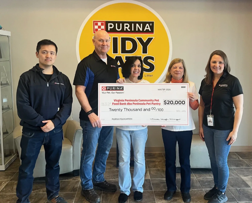Five people holding a $20,000 Purina Foundation check for Virginia Peninsula Community Pet Food Bank in front of a Purina Tid