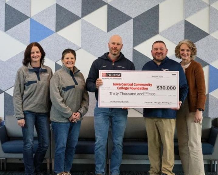 Five people stand in front of a geometric patterned wall holding a $30,000 check for Iowa Central Community College Foundatio