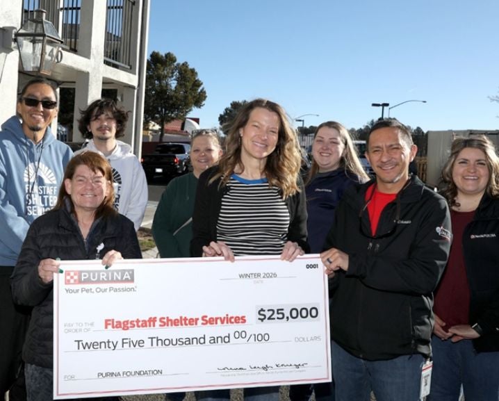 Group of people outdoors holding a $25,000 donation check from Purina to Flagstaff Shelter Services in winter 2026.