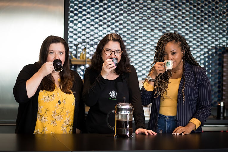 Three women enjoying coffee together at a counter, smiling and relaxed.