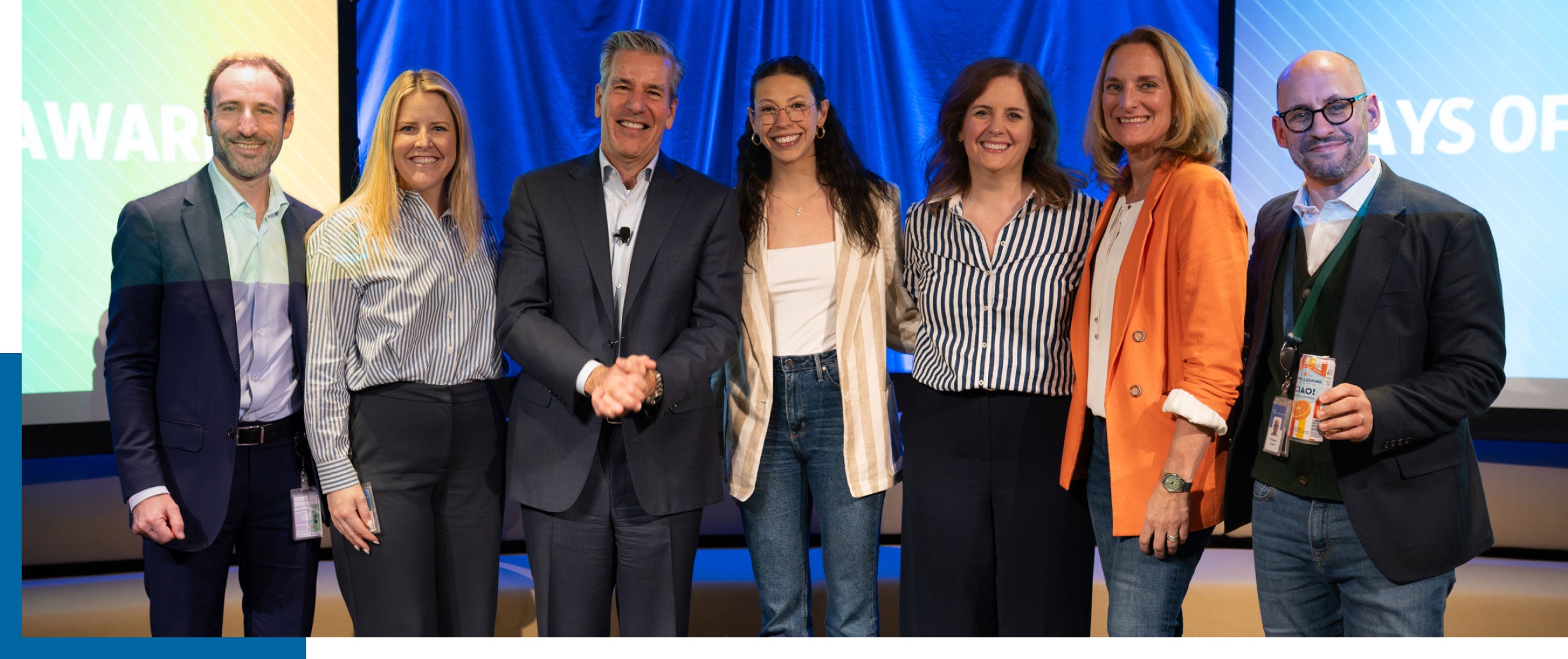 Seven people standing together on a stage, smiling at the camera.