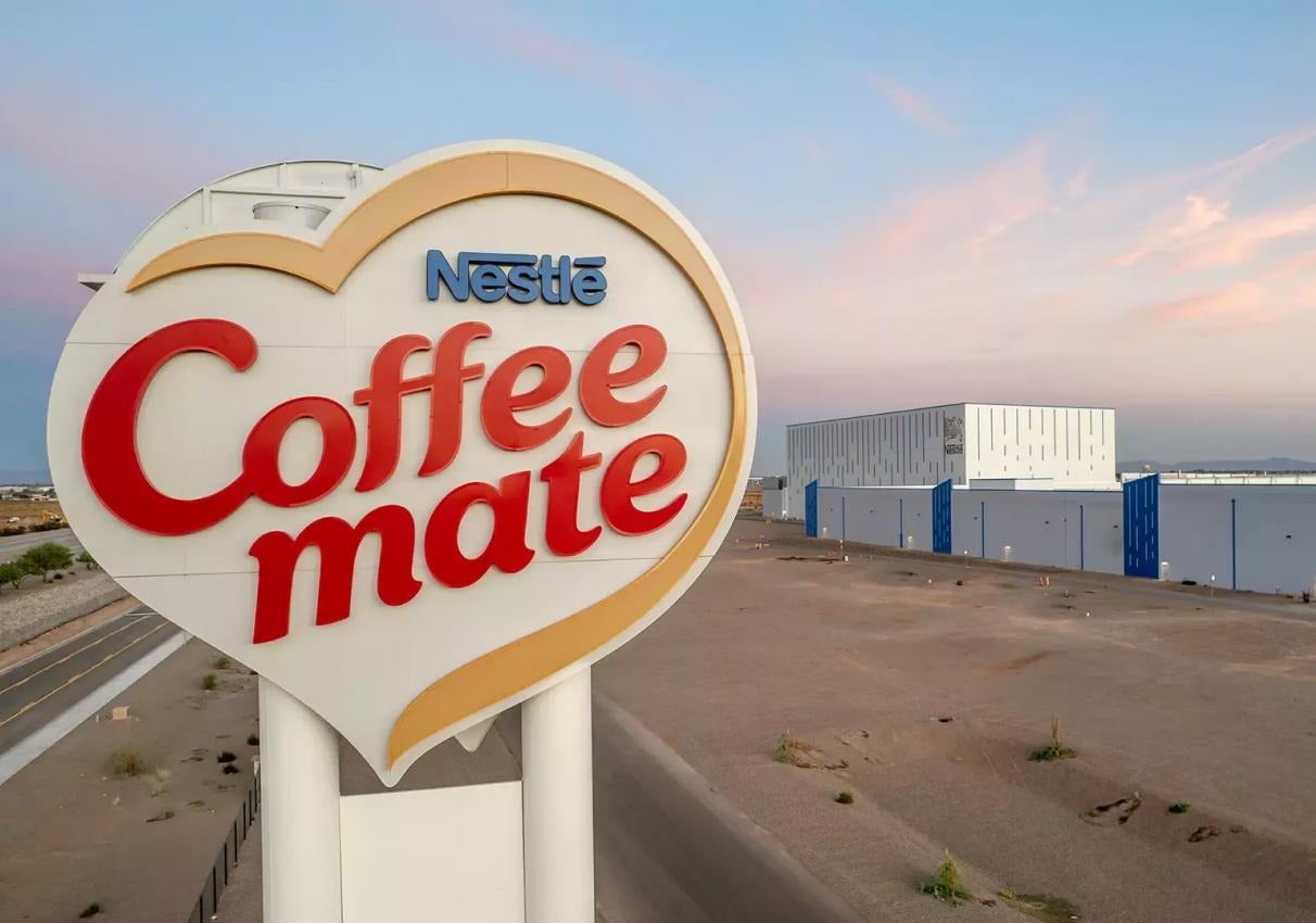 Large Coffee mate heart-shaped sign outside a modern industrial building at sunset.