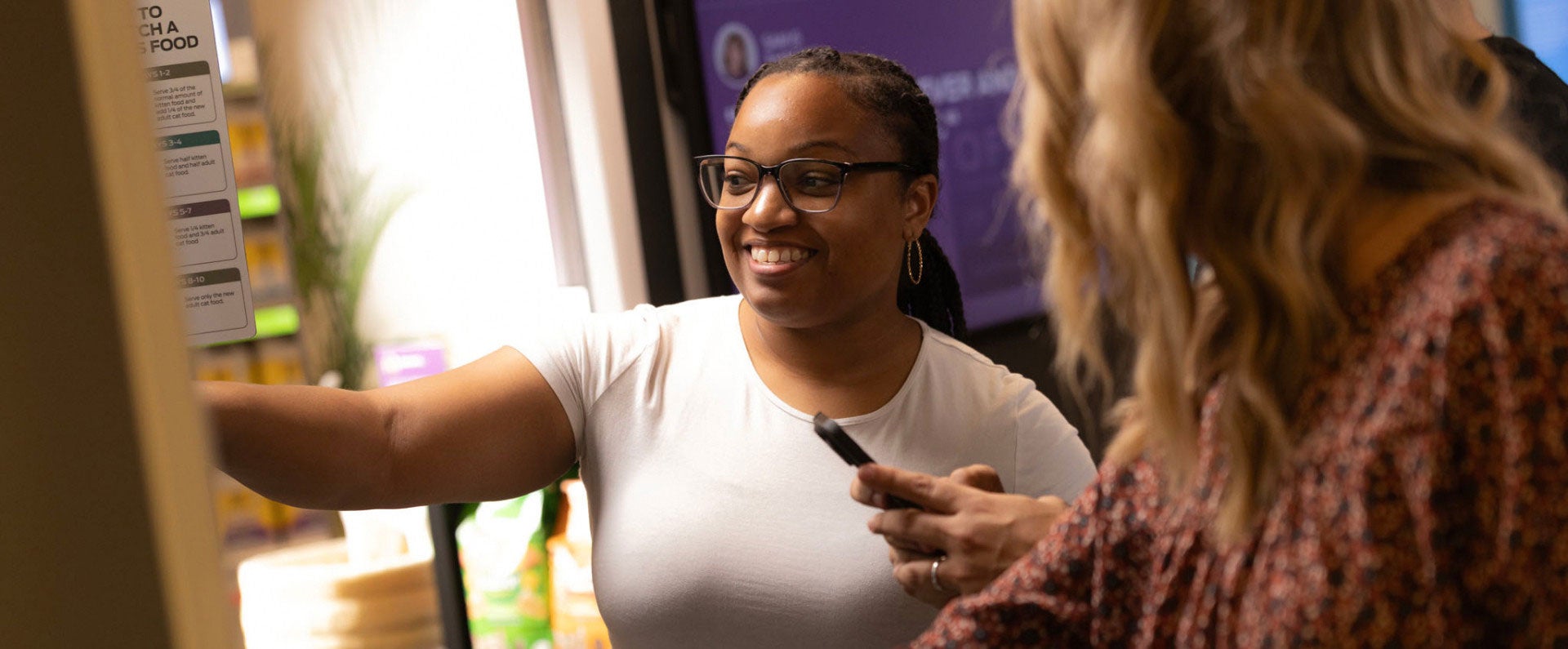 Two women smiling and interacting near a screen, one holding a marker.