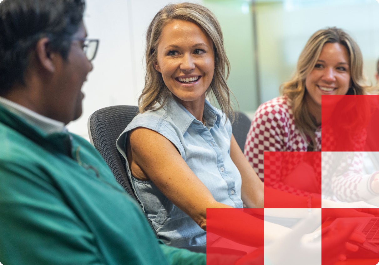 Three associates laughing together in a meeting