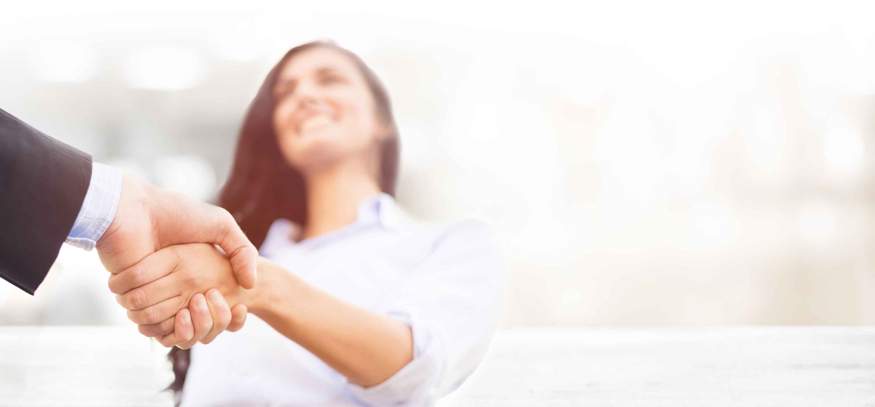 A smiling woman shakes someone's hand