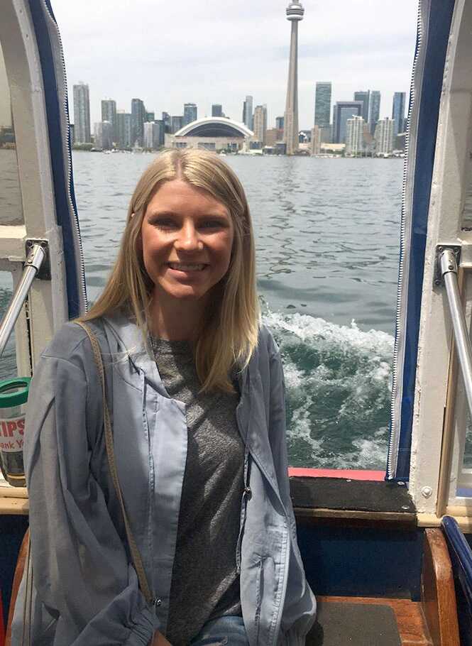 A woman sits on a boat with a city view