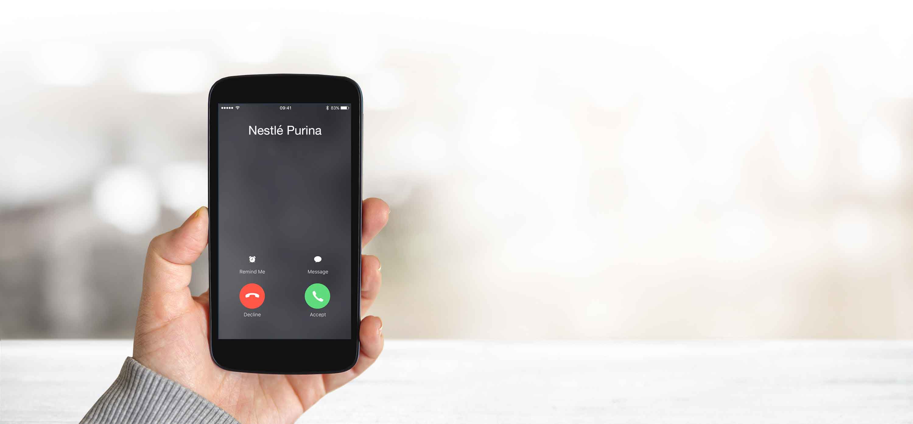 A hand holds a ringing phone in the blurred background
