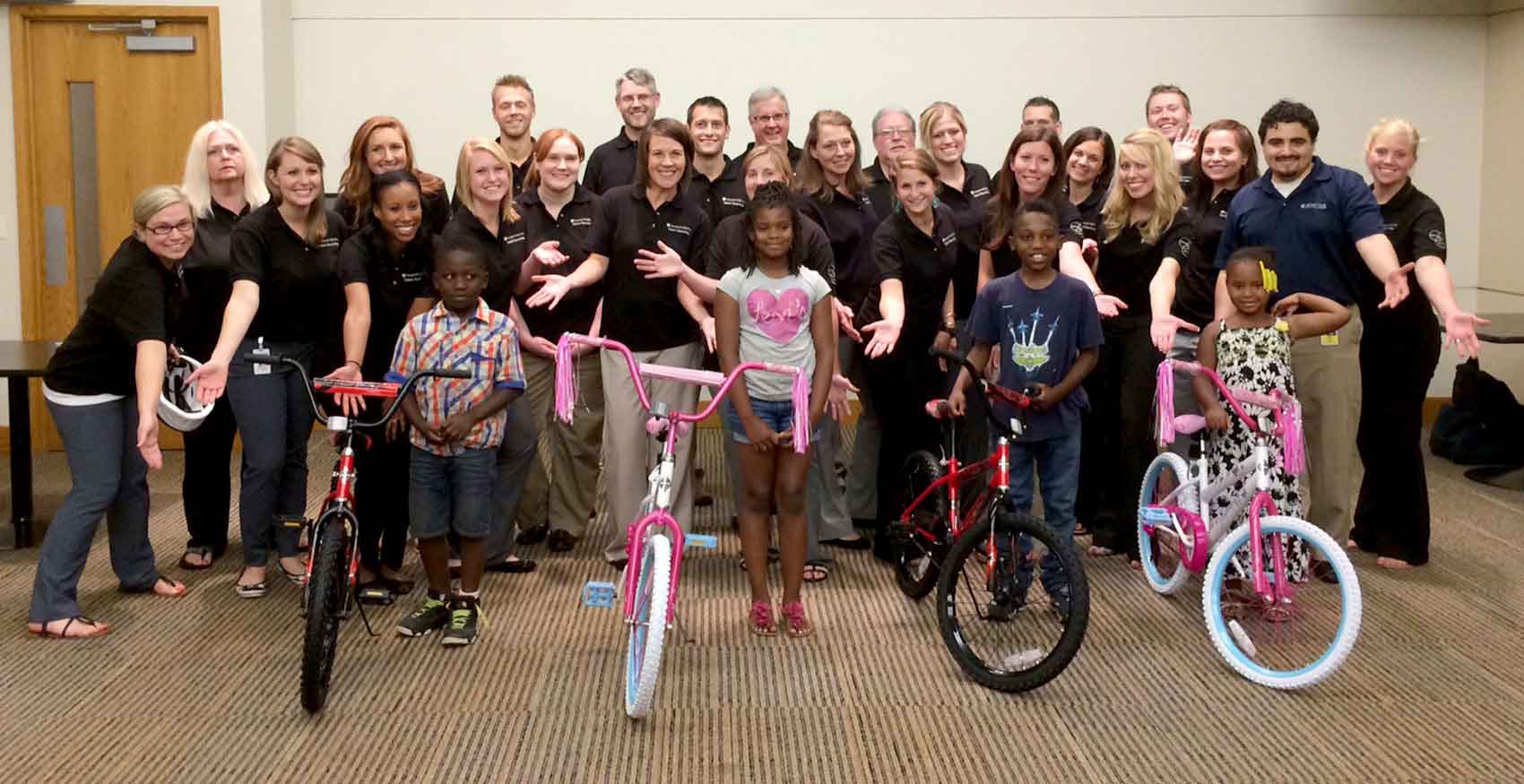 Large group of associates in black shirts with community children