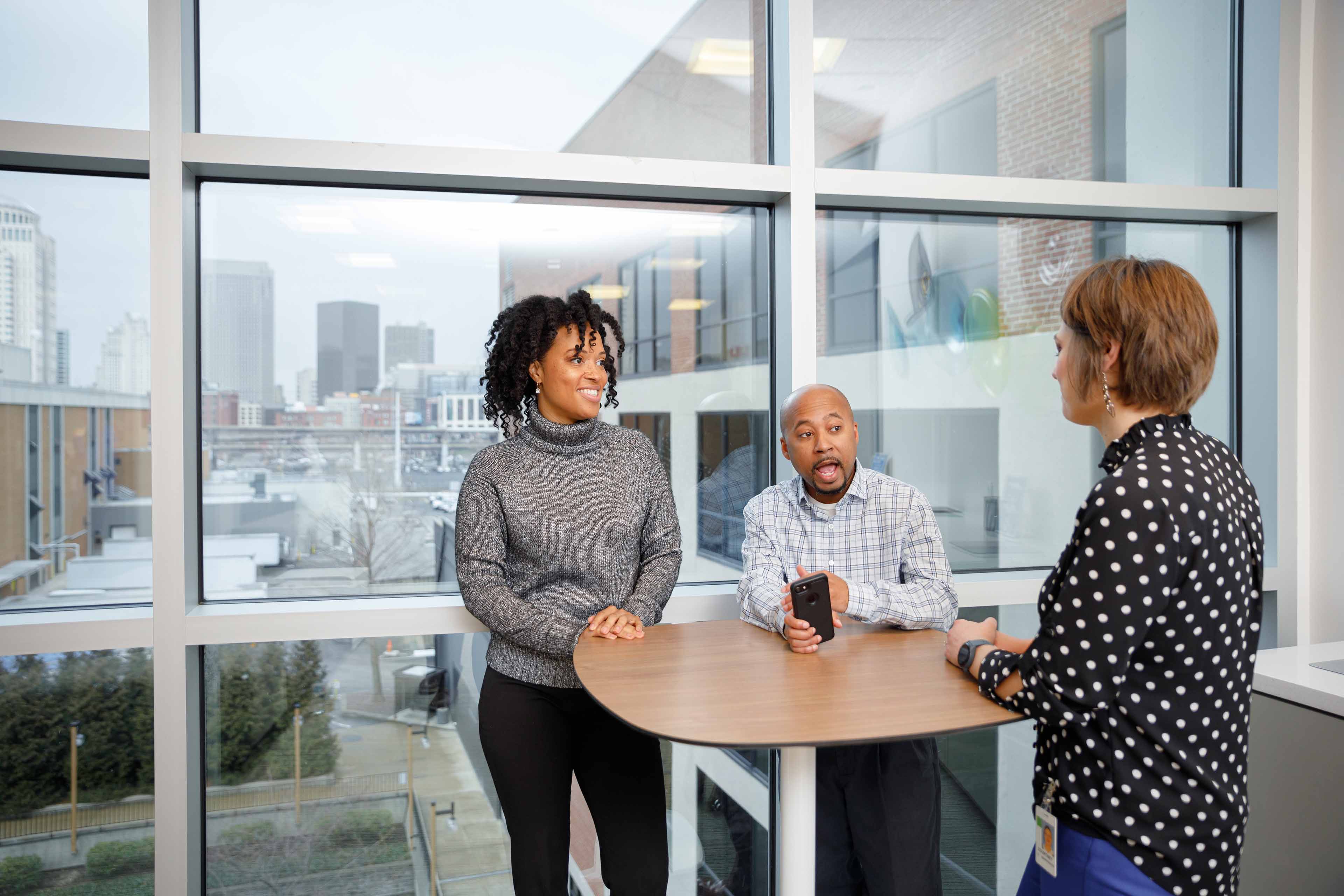 Two women and a man talk at a table
