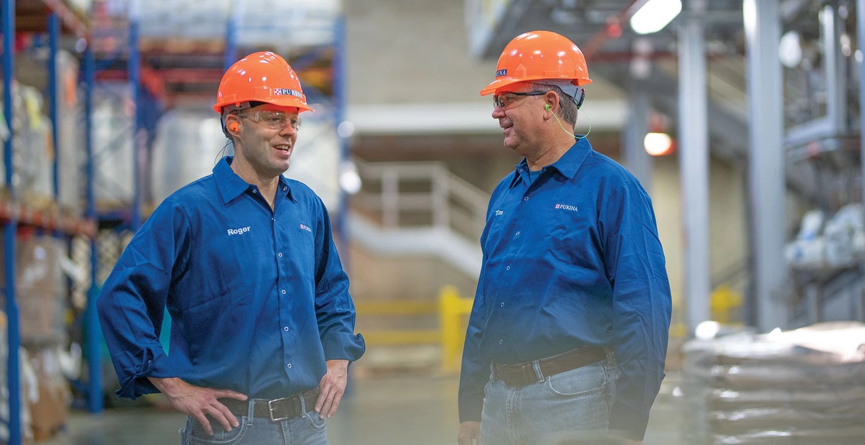 Two Purina factory workers talking in the warehouse