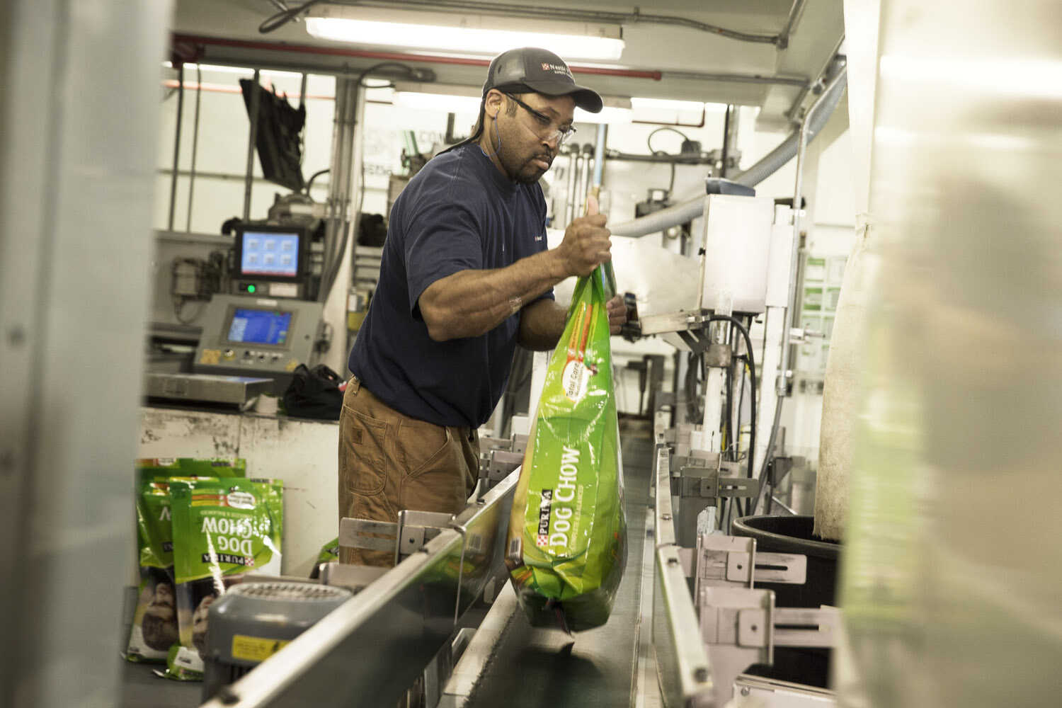 A man puts a dog chow onto a conveyor