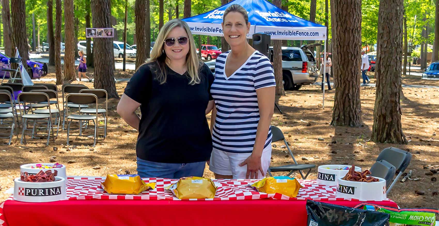 Two women standing at promotional Purina table outside