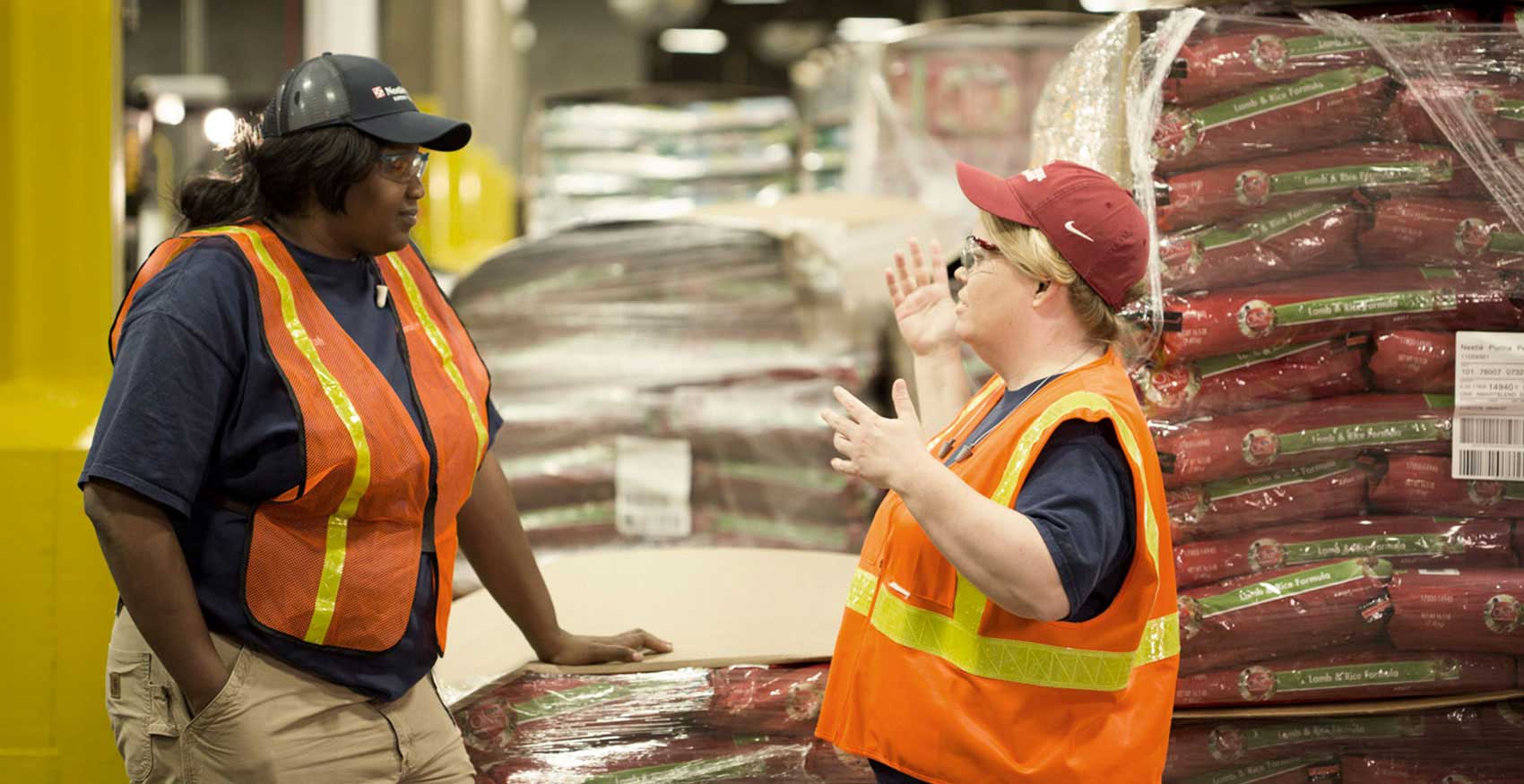 Women talking by Purina dog food pallets