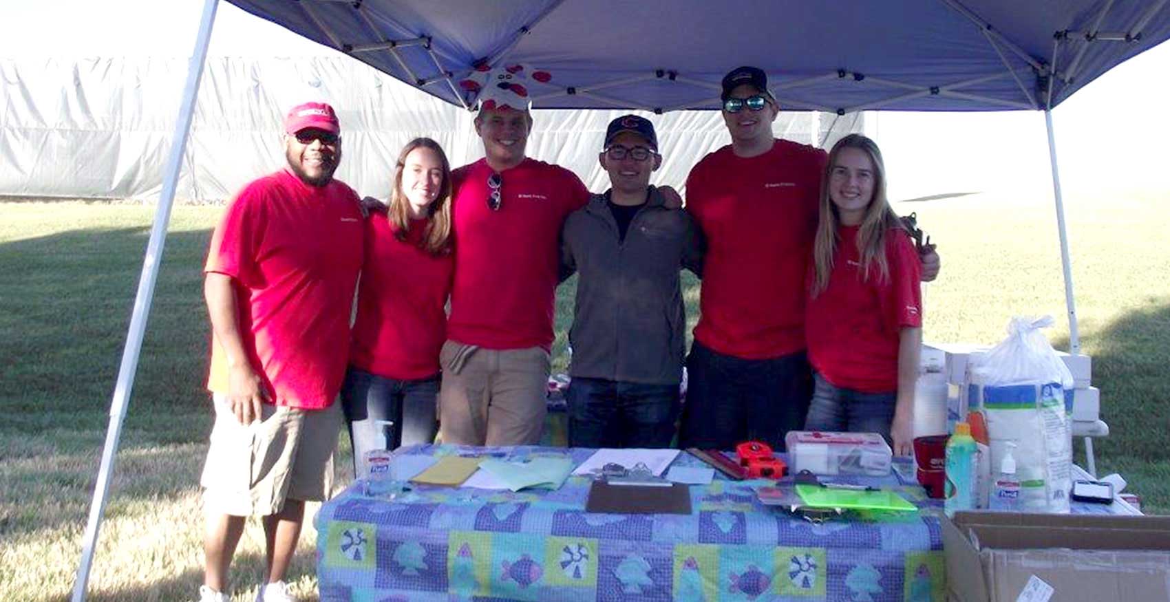 Associates standing together outside under tent