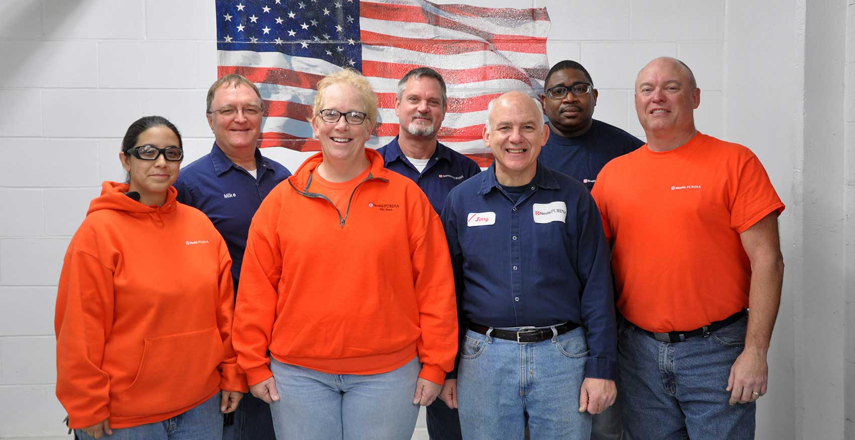 Associates standing in front of American flag painting
