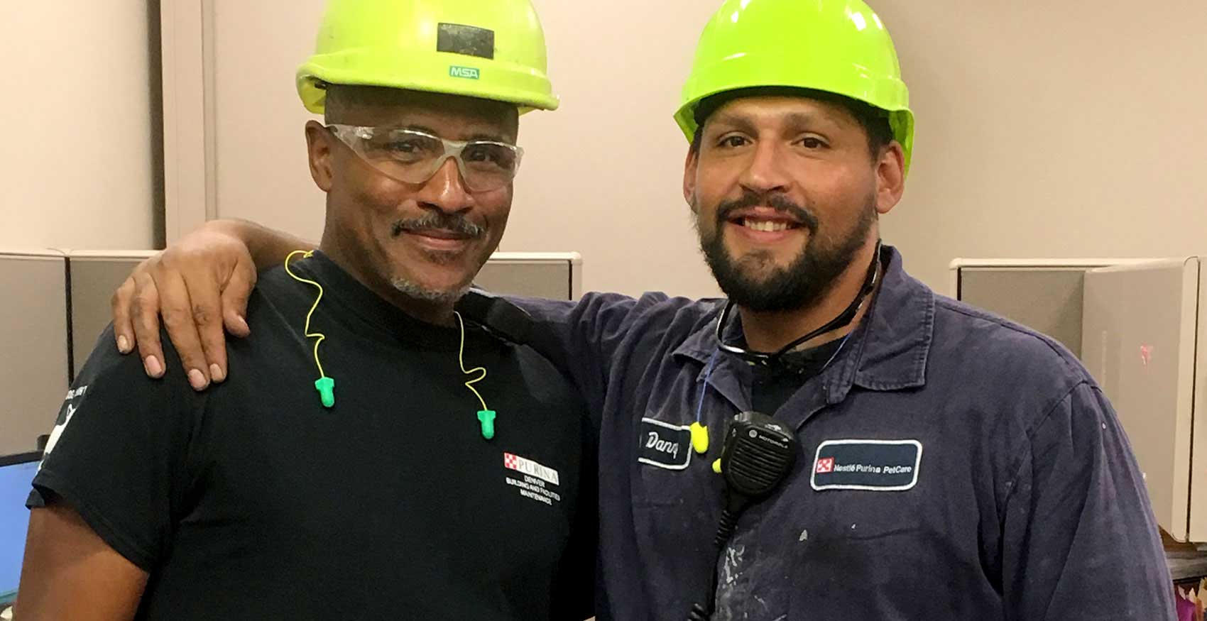 Two men smiling with hard hats on