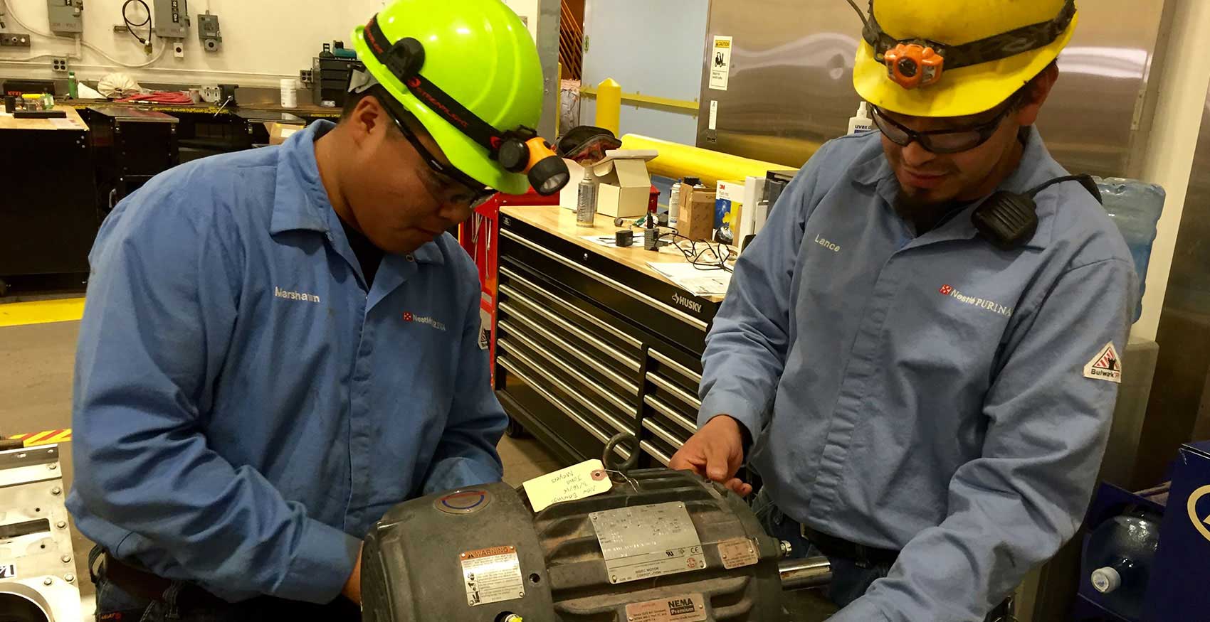 Associates working on factory floor with hard hats on