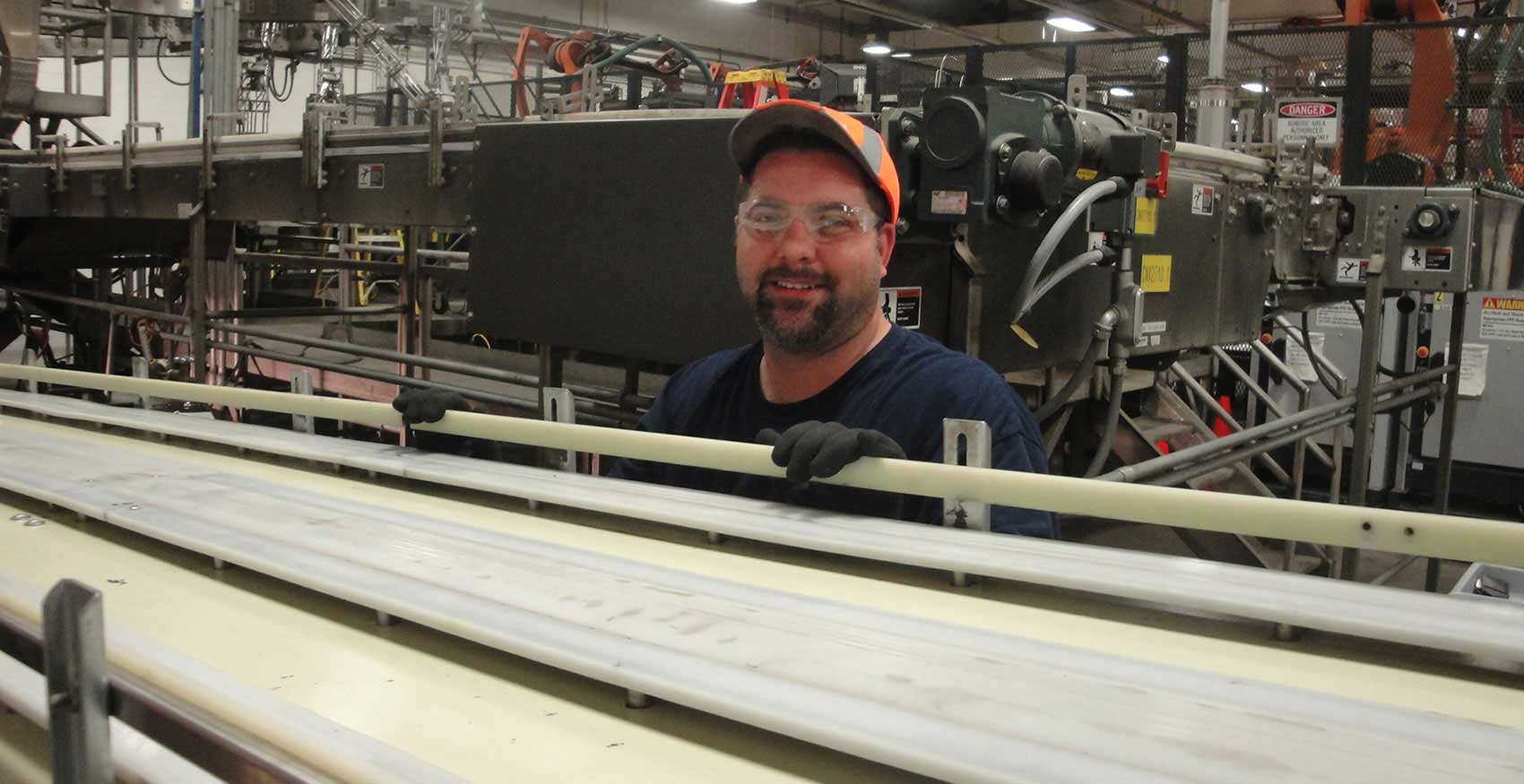 Man smiling with safety glasses on standing on factory floor