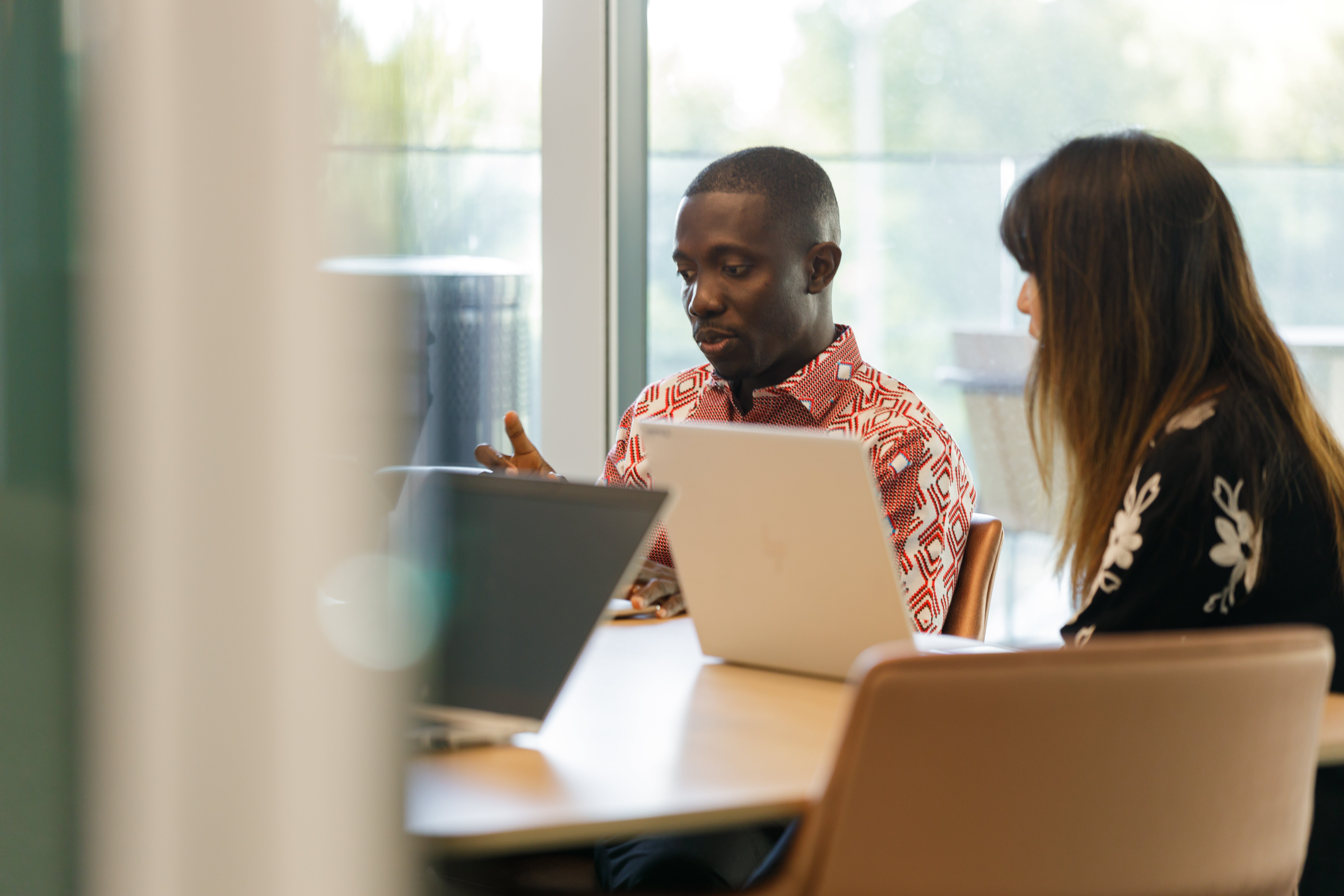 Man and woman sitting and talking over a laptop in a corporate meeting room
