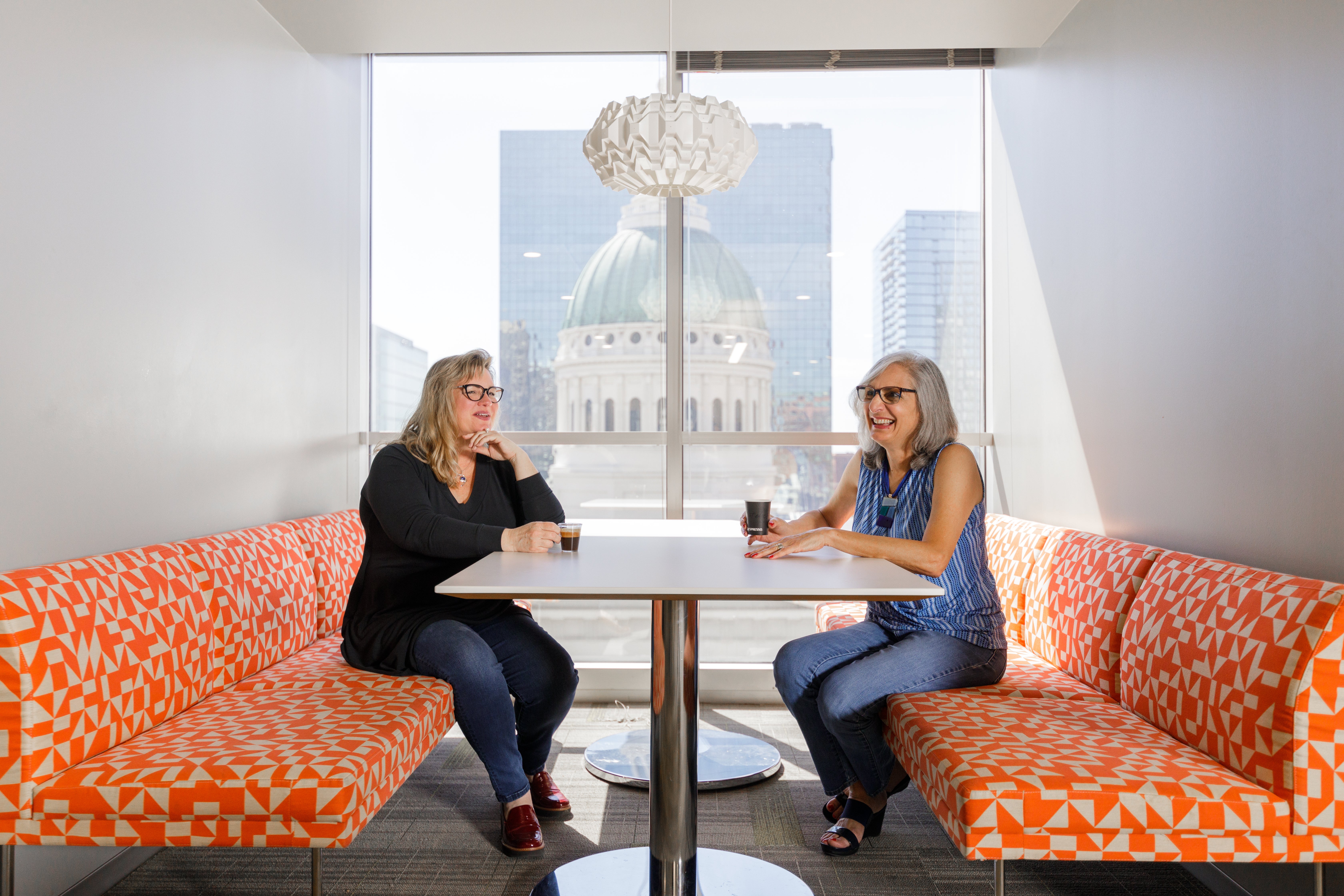 Two women sitting and talking at a booth at Nestlé USA corporate headquarters with monument