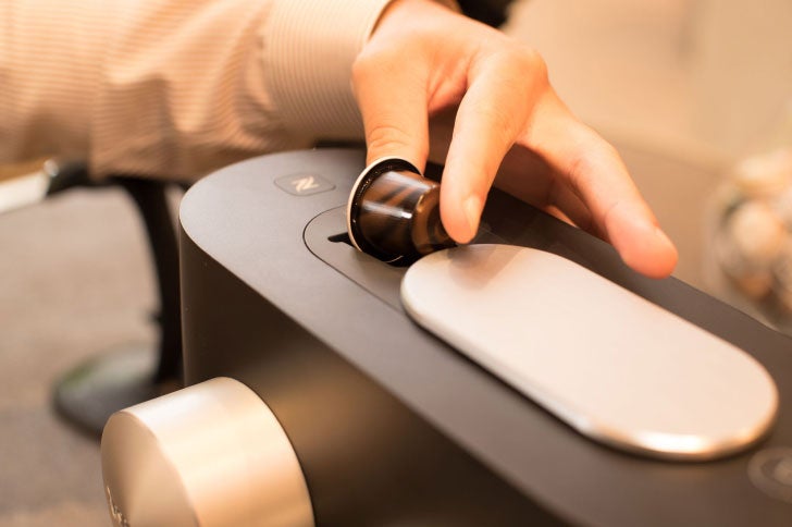 Hand placing a pod in Nespresso machine