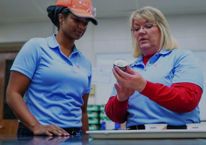 2 employees inspecting can in factory