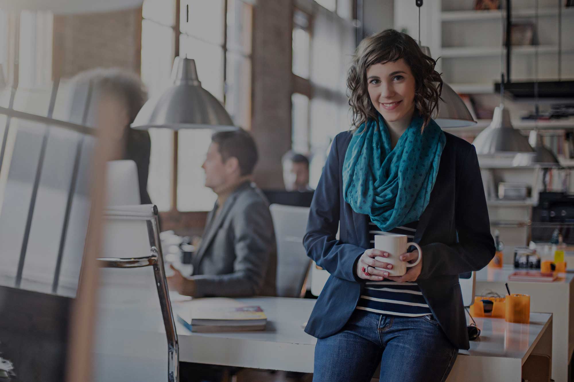 woman leaning on desk holding coffee