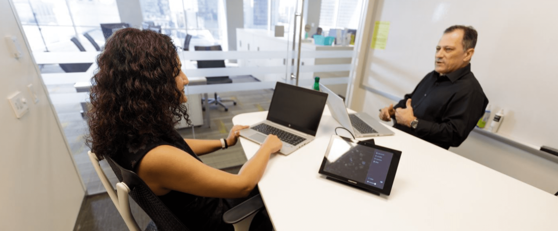 A man and a woman sit and converse in a meeting room
