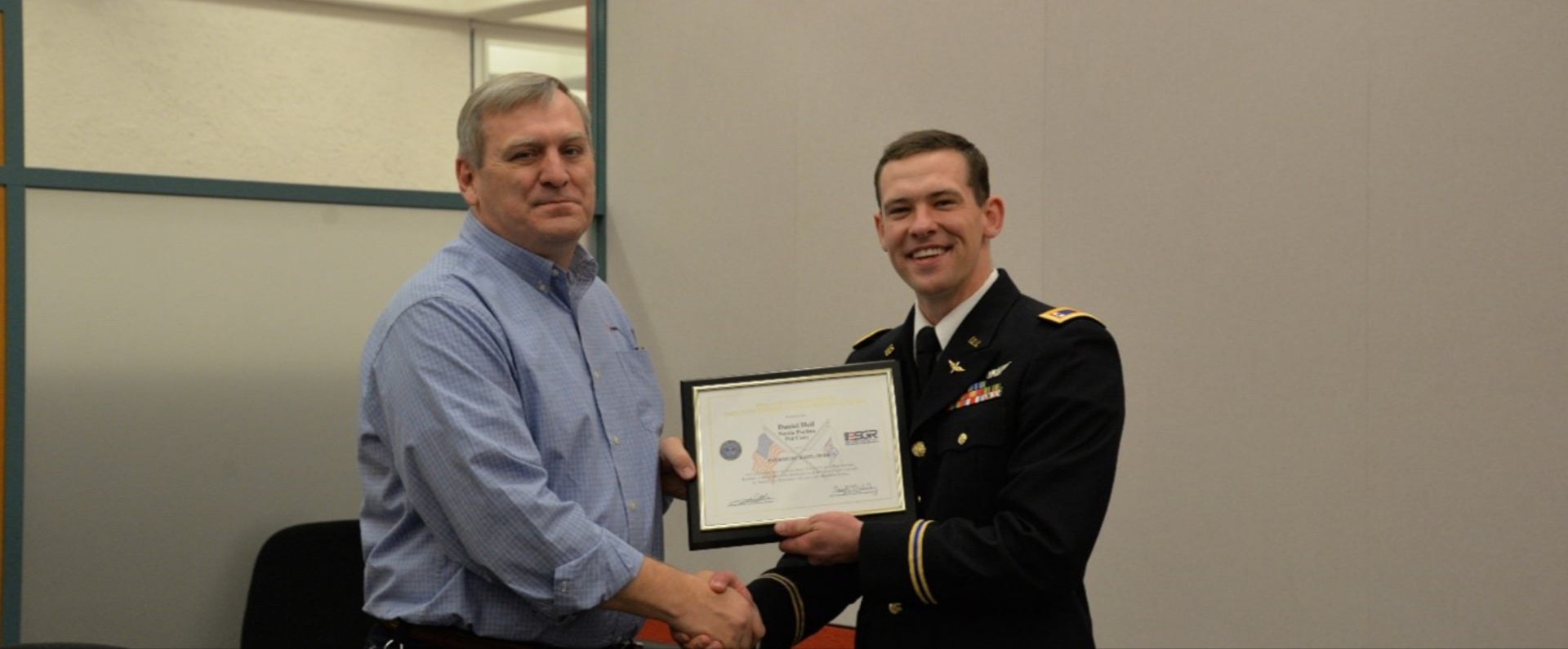 Associates smiling and shaking hands as one recieves an award