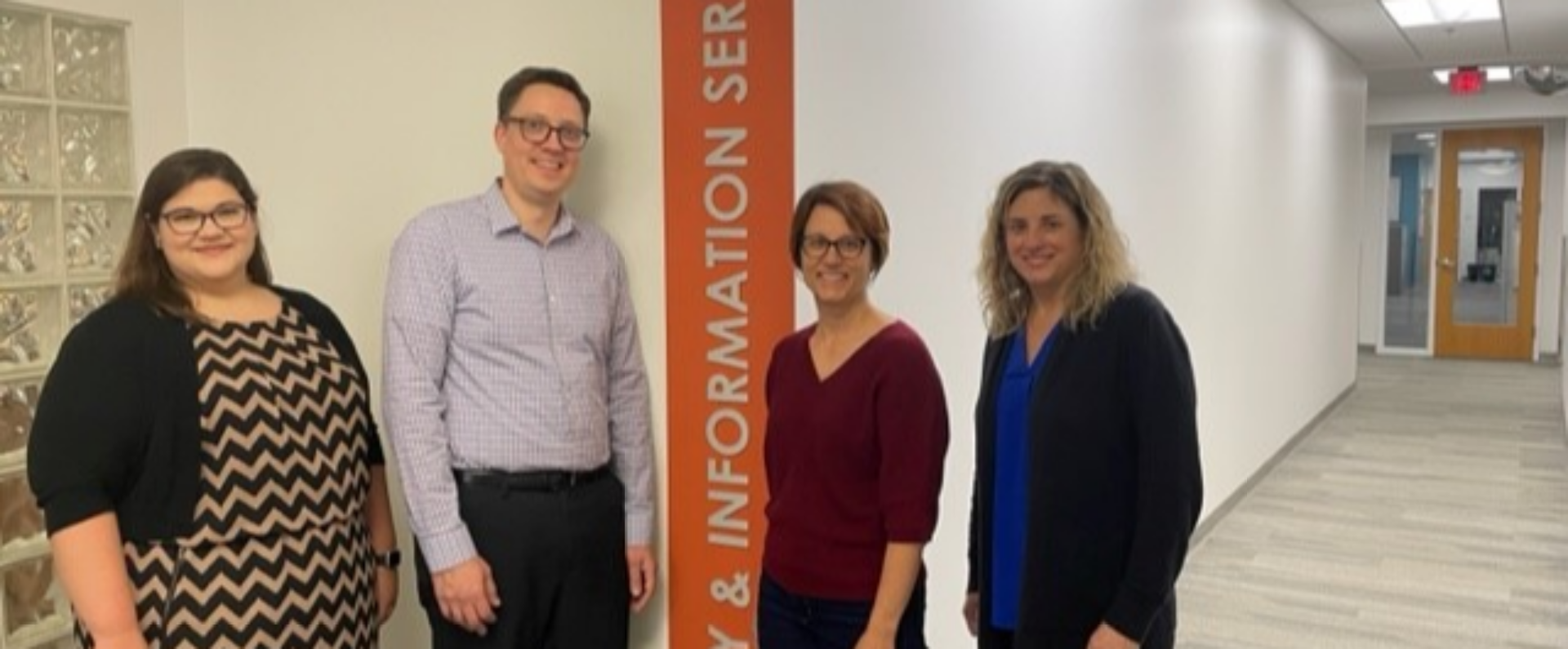 Group of four Nestlé Purina colleagues smiling in front of library information services