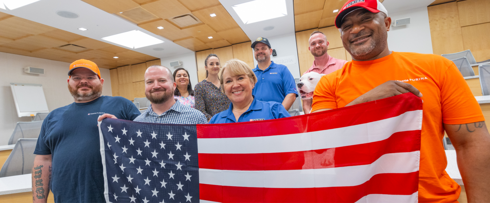 Nestlé Purina associates with military experience smile and hold American flag