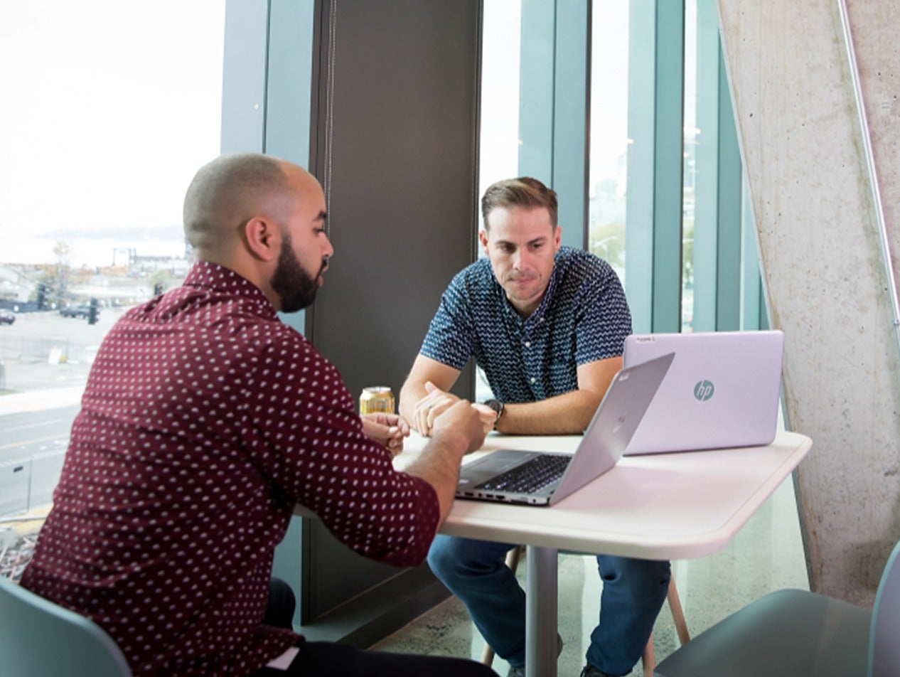Two men reviewing work on laptops