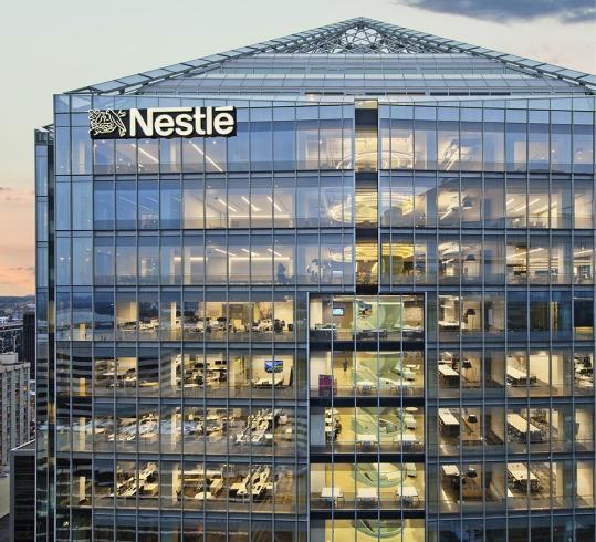Nestlé headquarters glass building with offices visible at sunset.