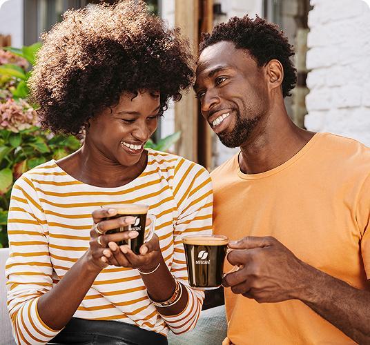 Smiling couple enjoying coffee together outdoors.