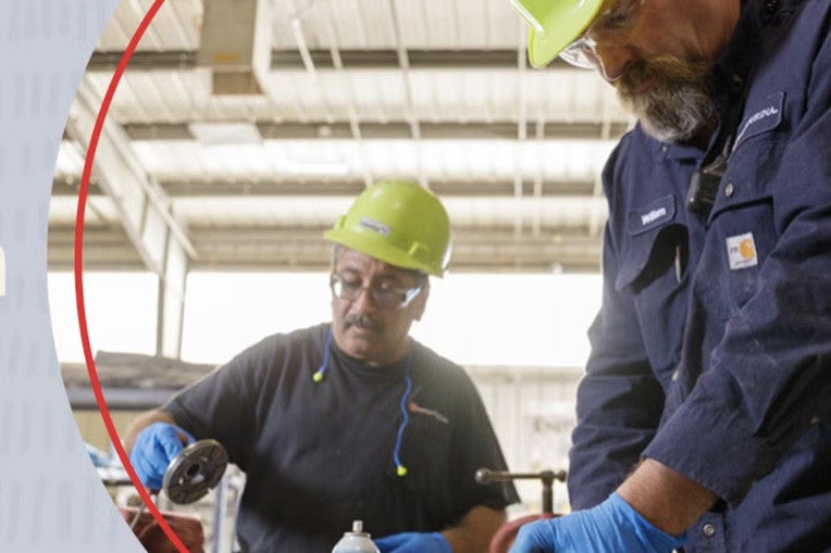 Two associates working with a grinder in a factory