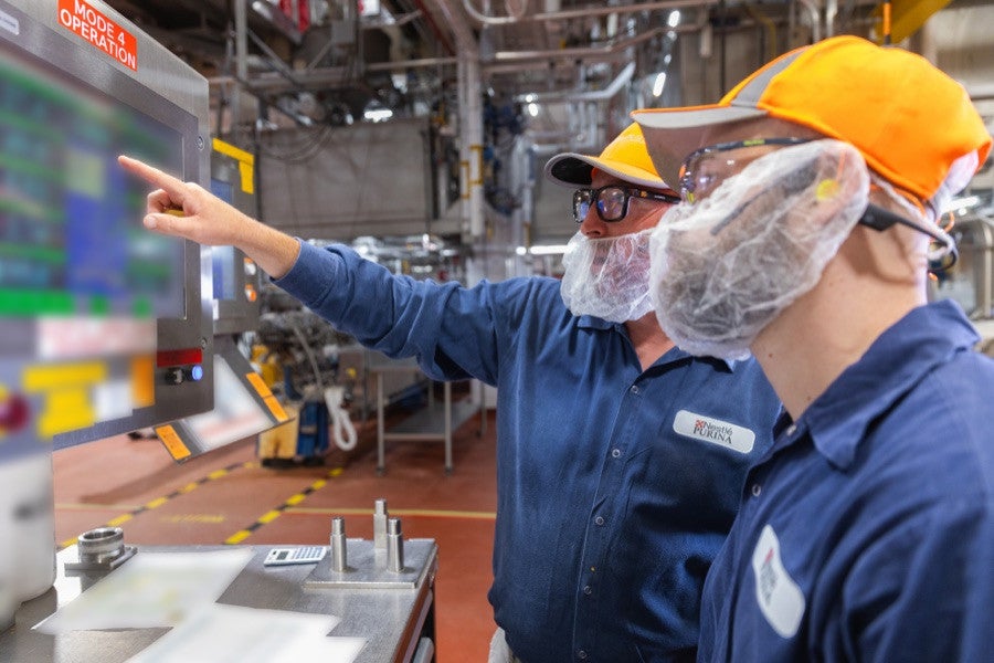 Factory associate in a hairnet and safety glasses working on a production line