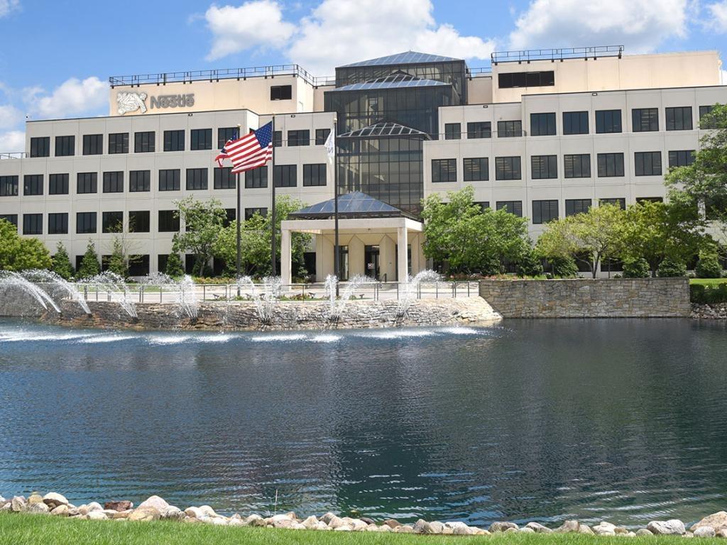 American flag waving outside modern Nestlé Solon campus with a water feature