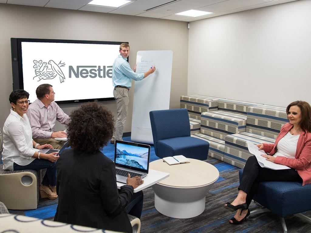 Team meeting in modern office with Nestlé logo on screen and whiteboard
