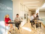 Collaborative Nestlé space with groups meeting at high tables near branded wall