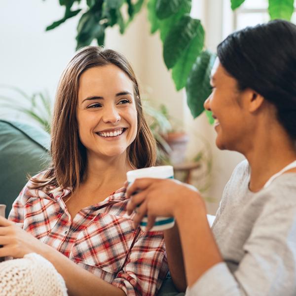 Two females drinking coffee on a couch