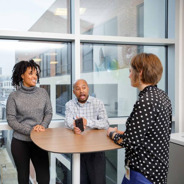 Two women and a man talk at a table