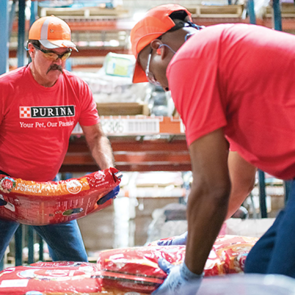 Two Purina factory workers stacking bags of pet food