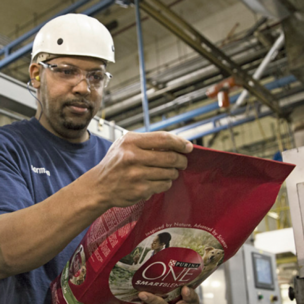 Purina factory worker carrying a bag of dog food