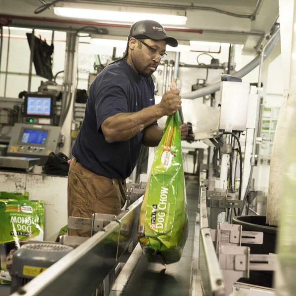 A man puts a dog chow onto a conveyor