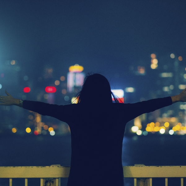 person holding their arms out as if to embrace the city