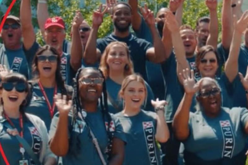A cheerful group of people in purina t-shirts and hats poses together for a memorable picture.