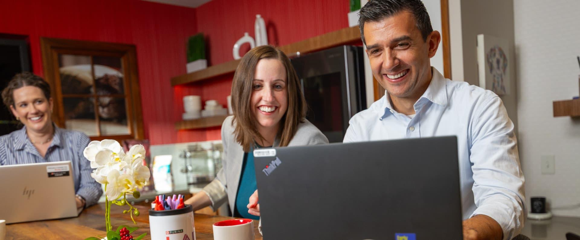 Smiling coworkers working together on laptops at a shared office table