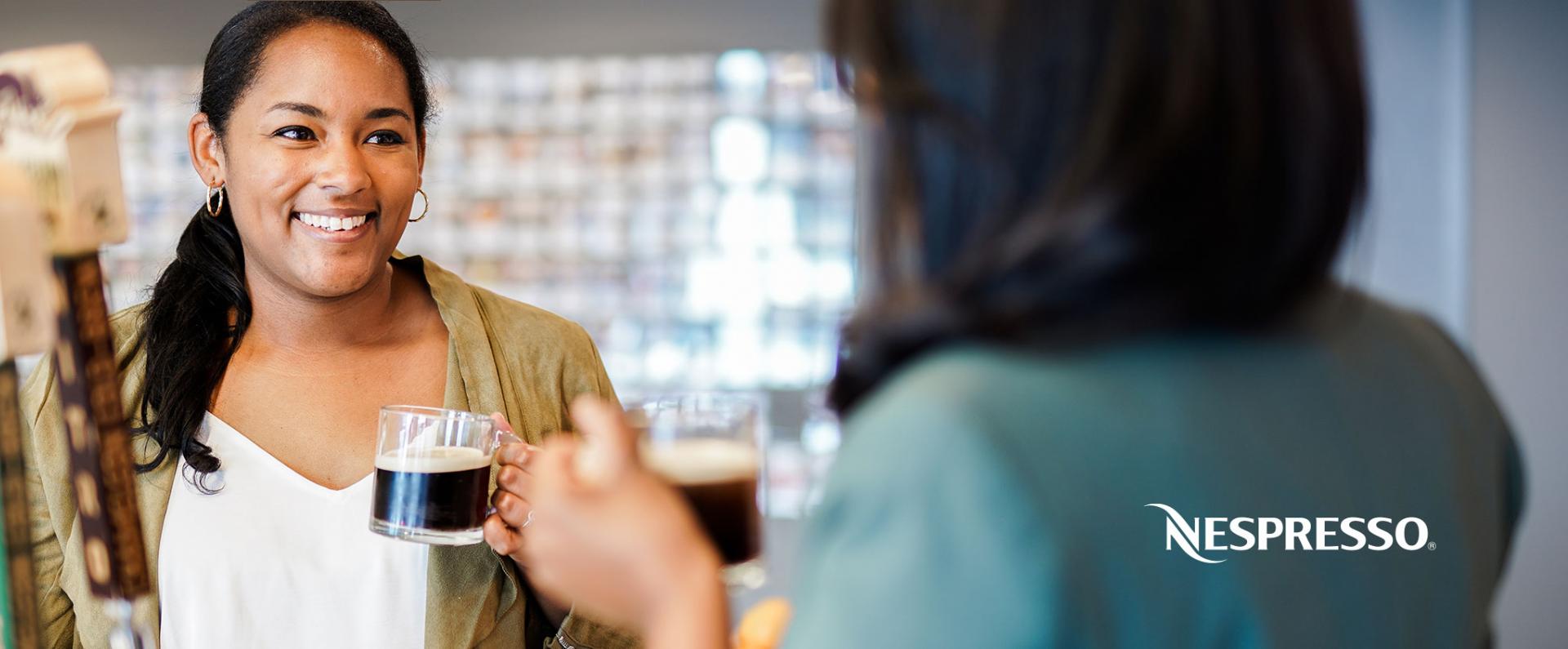 Two women smiling while drinking Nespresso in the office