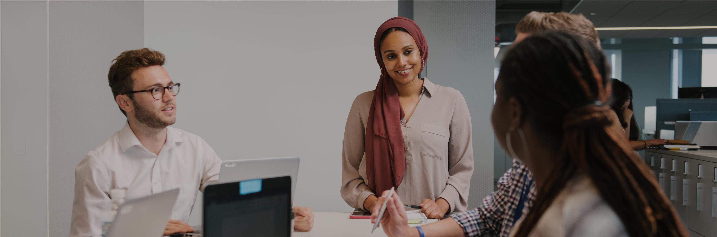 Four Nestle employees standing around a desk having a discussion